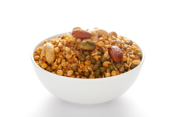 'Shahi Mixture' in a white ceramic bowl, made with peanut, cashew, corn flakes, almonds, etc. Pile of Indian spicy snacks (Namkeen). Side view, against the white background