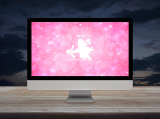 Cupid flat icon on desktop modern computer monitor with pink love heart screen on wooden table over sunset sky, Business internet dating online, Valentines day concept