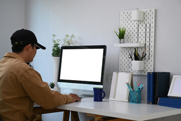 Young man sitting in comfortable workplace and working from home with computer.