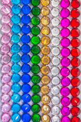 .Colorful diamonds are arranged neatly in a row on a white floor.