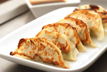 Japanese dumplings or Gyoza in white plate with gyoza sauce on a wooden table in a restaurant. Selective focus