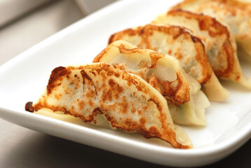 Japanese dumplings or Gyoza in white plate with gyoza sauce on a wooden table in a restaurant. Selective focus
