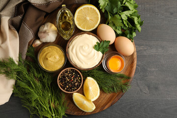Board with bowl of mayonnaise and ingredients for cooking on dark wooden background