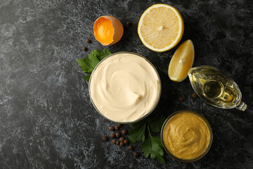 Bowl with mayonnaise and ingredients for cooking on black smokey background