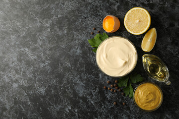 Bowl with mayonnaise and ingredients for cooking on black smokey background