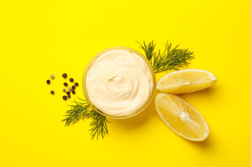 Bowl with mayonnaise and spices on yellow background