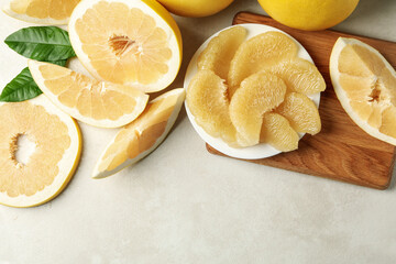 Ripe pomelo and plate with pomelo slices on white textured background