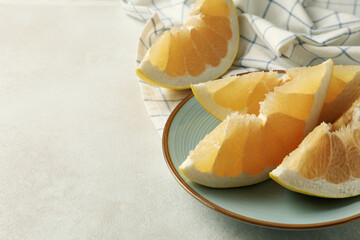 Kitchen towel and plate with pomelo slices on white textured background