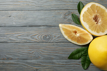 Ripe pomelo fruit and leaves on wooden background