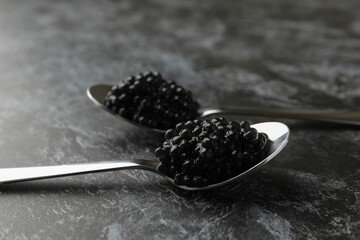 Spoons with black caviar on black smokey background