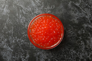 Glass bowl with caviar on black smokey background