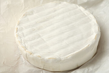 Delicious camembert cheese on paper, close up