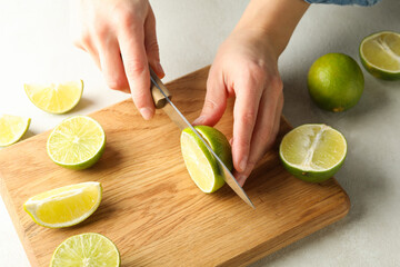 Woman cuts lime on cutting board, close up