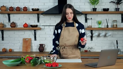 Housewife listen teacher chef study online video call conference webcam chat sliced fresh cherry tomato. Woman in home kitchen watching culinary webinar cooking healthy salad uses laptop computer