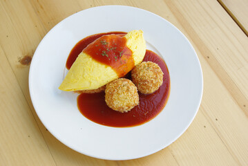 Japanese Omu Rice (fried rice with chicken and tomato sauce wrapped in egg omelet) topped with Hayashi sauce (sliced pork gravy)