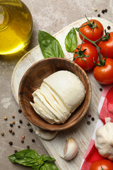 Concept of tasty eating with mozzarella and ingredients on board on gray textured table