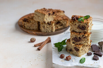 Oatmeal squares with chocolate, nuts, pieces of chocolate and mint, light concrete background. Diet bars. Healthy bakery for breakfast or dessert.