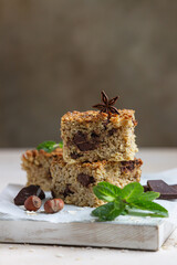 Oatmeal squares with chocolate, nuts, pieces of chocolate and mint, light concrete background. Diet bars. Healthy bakery for breakfast or dessert.