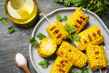 Delicious grilled corn cobs on grey table, flat lay