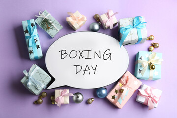 Speech bubble with phrase BOXING DAY and Christmas decorations on lilac background, flat lay