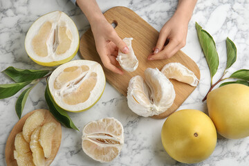 Woman with tasty ripe pomelo at white marble table, top view