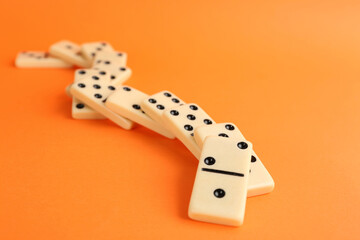 Fallen white domino tiles on orange background