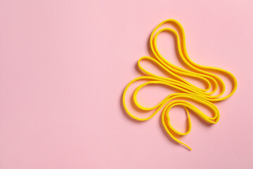 Fototapeta premium Yellow shoelace on pink background, top view. Space for text