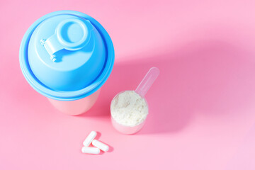 Protein shaker scoop and capsules on pink background top view