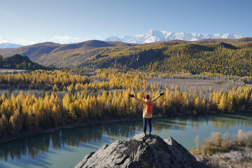 Fototapeta na wymiar Traveler Standing and Hands Raising on the Rock and Looking at the Chuya River Valley in Altai Mountains