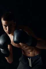 athlete in black boxing gloves on a dark background bodybuilder fitness 