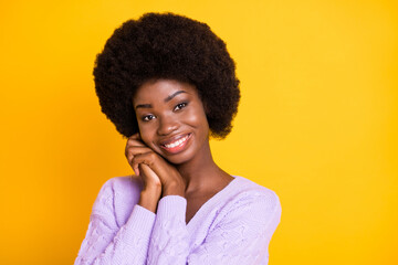 Photo of cute dark skin girl arms palms folded touch cheek toothy smile isolated on yellow color background