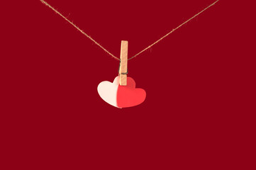 two hearts hanging on a clothespin on a red background