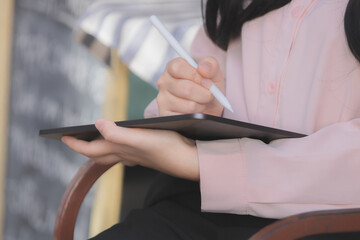 Close up of woman writing on tablet.