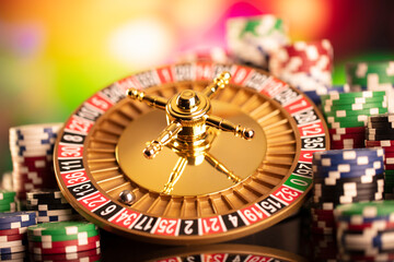 Casino theme.  Roulette wheel, poker chips and dice on  colorful bokeh background.