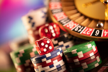 Casino theme.  Roulette wheel, poker chips and dice on  colorful bokeh background.