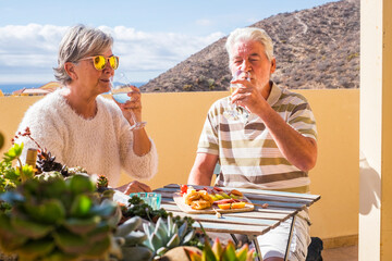 Senior caucasian couple enjoy together the afternoon cocktail time with wine and fruits onthe table...