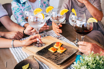 Close up of caucasian hands holding cocktail and wine glass all together on a table enjoying friendship and leisure fun  people and social distance or friendship