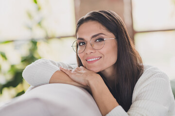 Photo of cheerful girl sit sofa rest head arms beaming smile wear eyeglasses white sweater in...