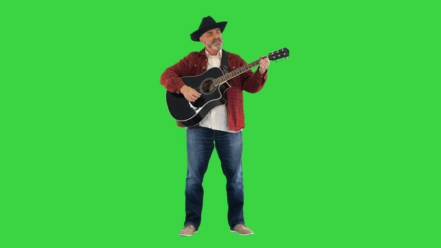 Man in cowboy hat playing on guitar and singing on a Green Screen, Chroma Key.