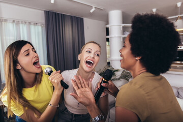Group of young women spend free time in karaoke, sing and have fun together, with friends, at home.