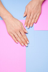Beautiful Female Hands with French manicure over colorful paper background