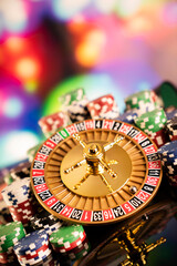 Casino theme.  Roulette wheel, poker chips and dice on  colorful bokeh background.