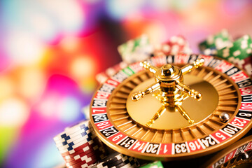 Casino theme.  Roulette wheel, poker chips and dice on  colorful bokeh background.