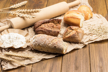 Pieces of bread, rolling pin and sprigs of wheat on paper. Wheat flour and grains