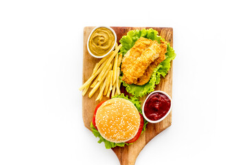 Top view of delicious burgers on on wooden board. Fried potatoes and chicken