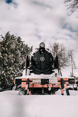 Beautiful image of an old locomotive in the nature with some snow on it. Concept of background of a snowy day. Vertical picture