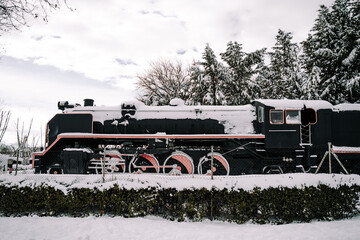 Beautiful image of an old locomotive between the nature with some snow on it. Concept of background of a day snowy