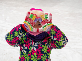 Cute child wearing colorful winter clothes pink hat playing snow on white nature landscape. Snowy winter holidays family active rest. Little funny girl smiling laughing having fun throwing snowballs