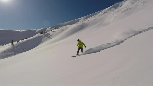 Full speed riding in backcountry on a snowboard in a sunny winter day in the mountains