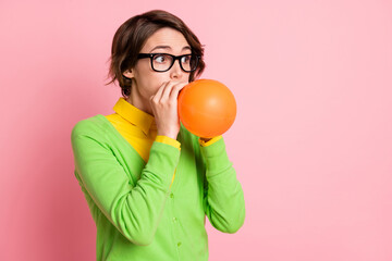 Photo of pretty young woman inflate balloon prepare celebration event look copyspace isolated on pastel pink color background